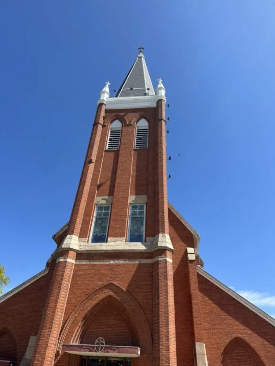 Brick church with tall steeple and cross